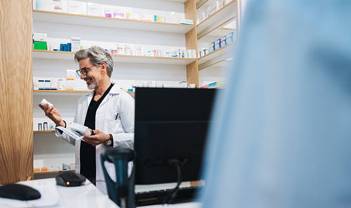 Mature pharmacist reading medication label in a drug store