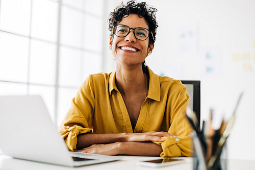Business woman looking thoughtful as she is sitting at her desk