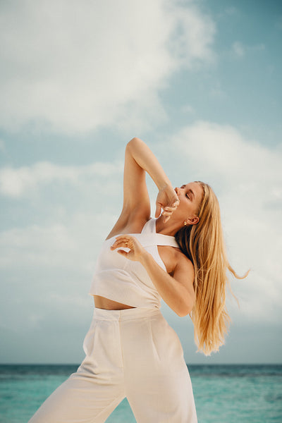 Elegant woman striking a pose on a serene beach under a clear sky