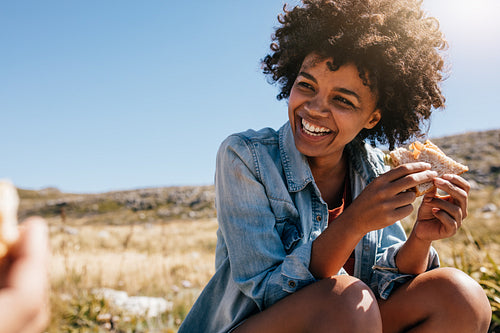 Happy young woman taking break during country hike.