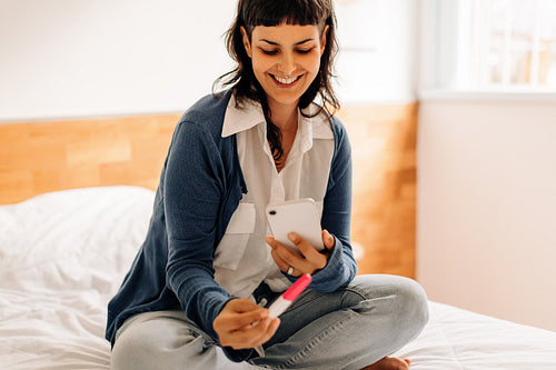 Happy young woman capturing her home pregnancy test results
