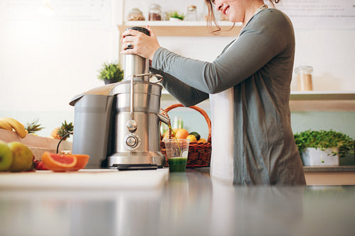 Young female bar employee making fruit juice
