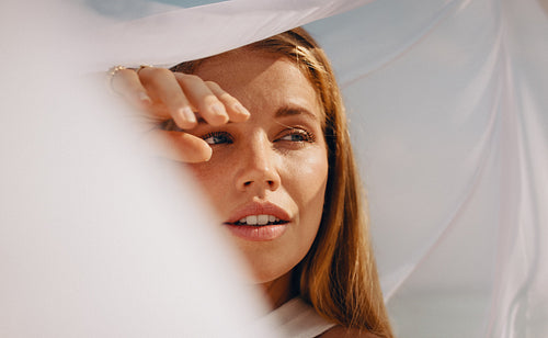 Young woman shielding her face from sunlight with serene expression outdoors