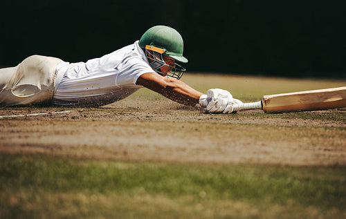 Cricket player diving to reach the crease on a sunny day