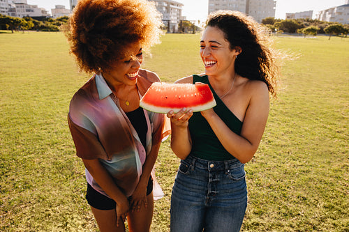 Joyful young friends enjoying summer outdoors with watermelon, capturing the essence of friendship and happiness