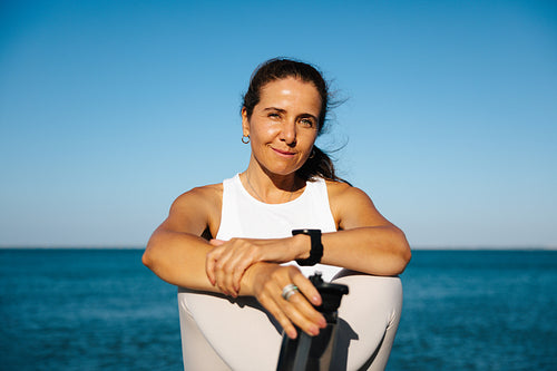 Confident woman exercising outdoors on a sunny day with the ocean in the background