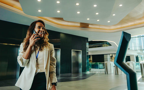 Confident Indian business professional on phone in modern foyer