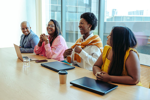 Diverse creative agency team in a joyful business meeting with laptops and coffee