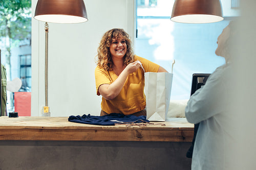 Store owner packing customer purchases in paper bag