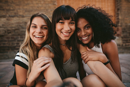 Three beautiful smiling girlfriends taking selfie