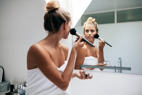 Beautiful female applying cosmetics on her face