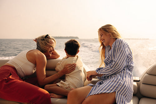 Mother, daughter, and grandson delighting in a holiday sunset on a boat.