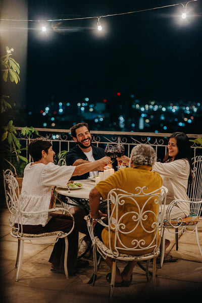 Family raising glasses in a toast during outdoor dinner at night