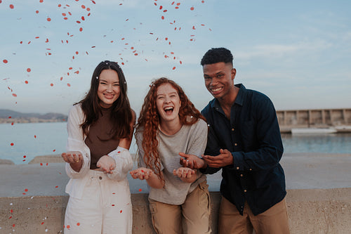 Group of friends celebrating with red and white confetti