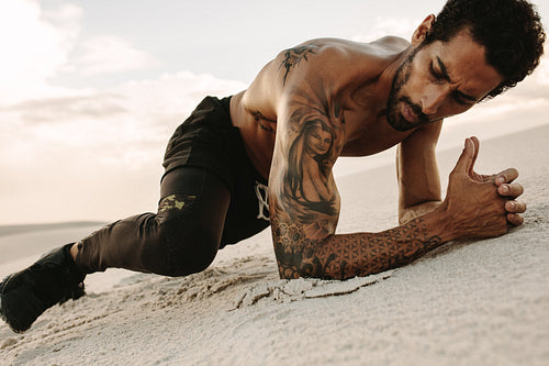Healthy man exercising on sand dunes