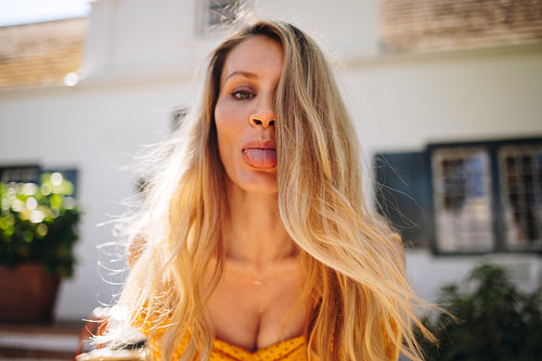 Playful young woman sticking her tongue out outdoors