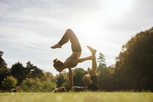 Healthy young couple doing acro yoga outdoors