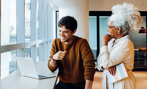 Two colleagues share a laugh at a laptop