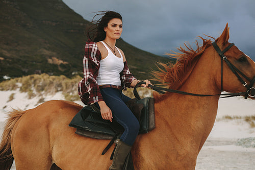 Woman riding with her stallion on the beach