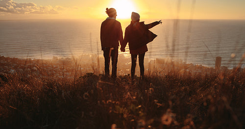 Traveling couple overlooking the seascape during sunset