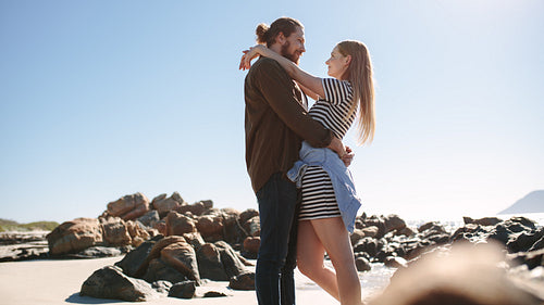 Romantic couple embracing on the rocky beach