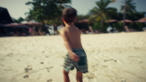 Little boy happily running on a pristine white sand beach during his summer vacation
