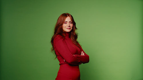 Confident woman in red with crossed arms poses against green screen