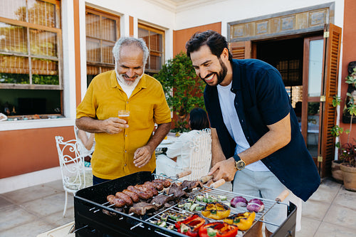 Father and son enjoying a barbecue during a sunny backyard gathering
