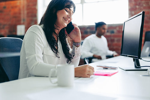 Smiling businesswoman taking a phone call in the office