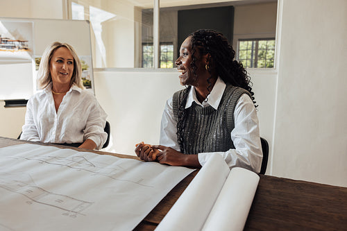 Two female architects discussing blueprints in a modern office environment
