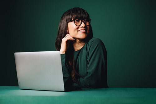 Computer work looks relaxed as a woman smiles in a green studio