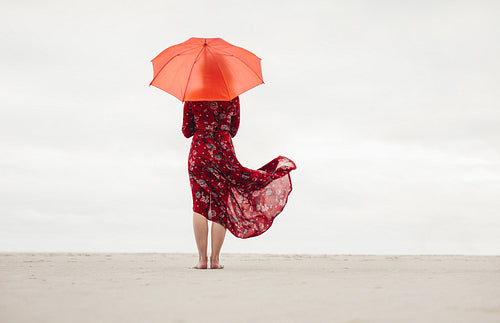 Woman under umbrella standing at the seaside