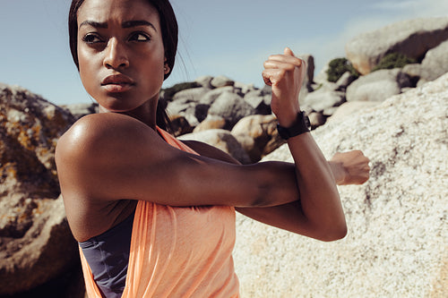 African woman stretching arms at the beach