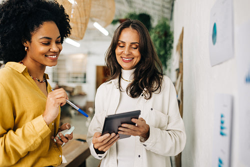 Female entrepreneurs using a tablet together as they brainstorm in an office