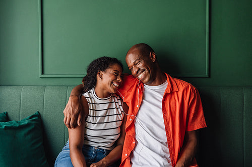 Happy couple laughing together on a cozy green couch