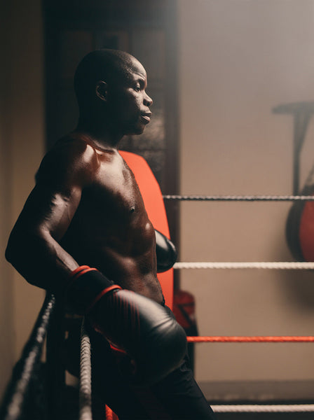 Shirtless young boxer taking a break in a boxing ring