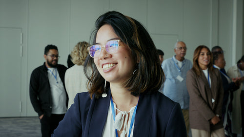 Young professional woman smiling confidently at a diverse business conference
