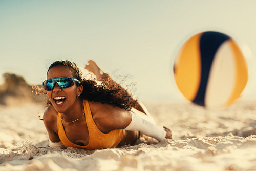 Dynamic beach volleyball game: Athlete dives for a dig on sandy seashore