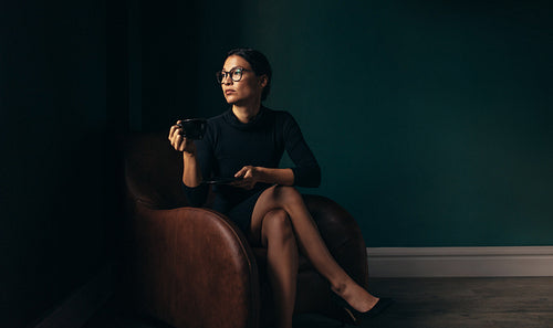 Businesswoman sitting on chair and having coffee