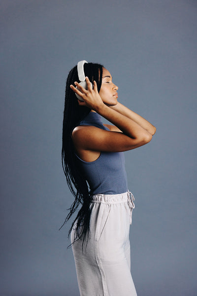 Sideview of a girl with braids listening to music on headphones