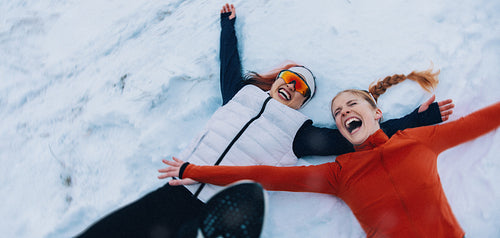 Female athletes enjoy making snow angels and laughing in winter wonderland after training