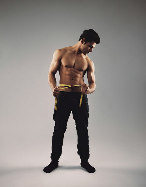 Masculine young man measuring his waist.