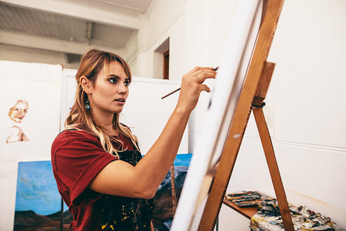 Woman painter painting on canvas in her studio