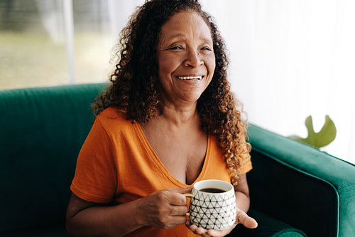 Morning coffee for retired senior: Woman relaxing on her couch with a hot beverage