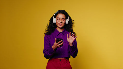 Young woman dances and enjoys music on her phone
