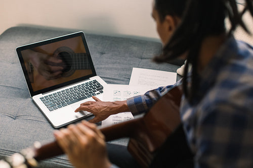 Male musician having online guitar lessons during quarantine
