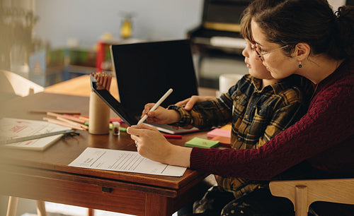 Boy learning to write with help from mother