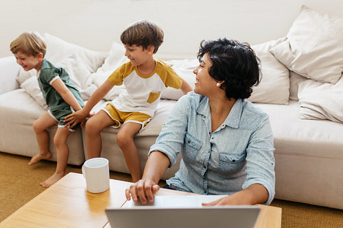 Kid playing at home with mom working on laptop