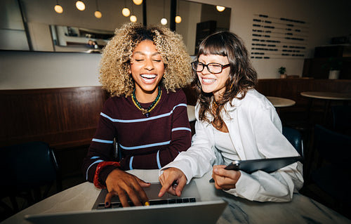 Friends and coworkers laughing together over a laptop