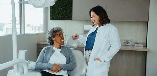 Friendly dentist guides senior patient in a contemporary dental clinic